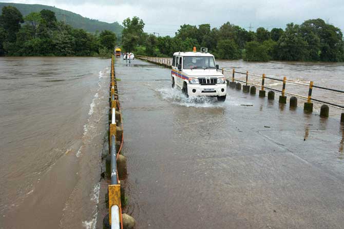 पश्चिम महाराष्ट्रात गेल्या तीन दिवसांपासून सुरू असलेल्या मुसळधार पावसामुळे कोयना नदीवरील नेरळे येथील पुलावर पाणी आले आहे. याच पुलावरून गस्त घालण्यासाठी निघालेले पोलिस. (पीटीआय)