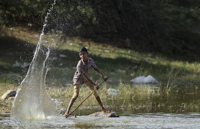 हैदराबादमधील एका तलावात पाण्याशी खेळताना हा लहान मुलगा. (छाया- एपी)