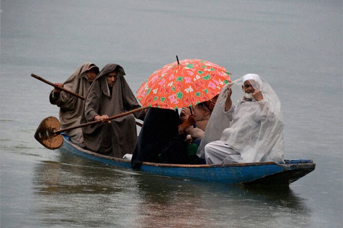 श्रीनगर येथील दल सरोवर पार करतना गरूवारी हे कुटुंब पावसाच्या तडाख्यात सापडले. (छाया: पीटीआय)