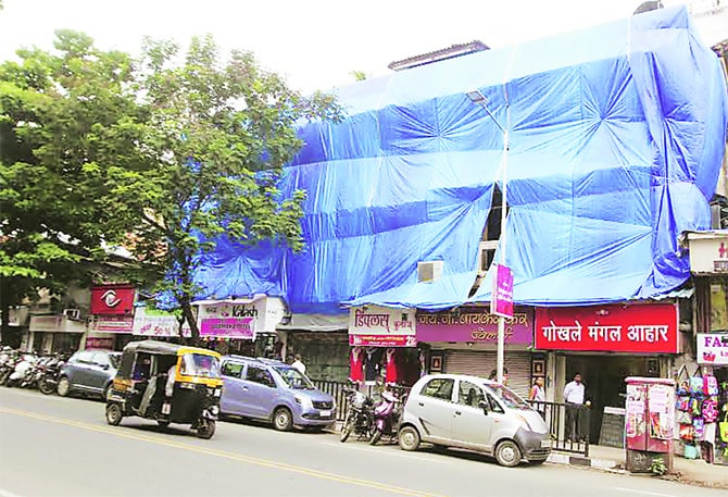 पावसाळ्यात इमारतीची अवस्था अधिक खराब होऊ नये म्हणून काही ठिकाणी प्लॅस्टिक अंथरलेले दिसते. (छाया- दीपक जोशी)