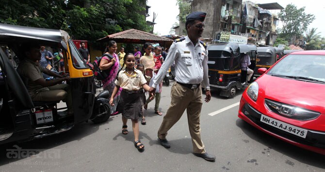 वाहनांच्या गर्तेत हरवलेल्या शहरातून विद्यार्थ्यांना शाळेत जाण्यासाठी मदत करणारा वाहतूक पोलीस अधिकारी. (छाया- नरेंद्र वास्कर)