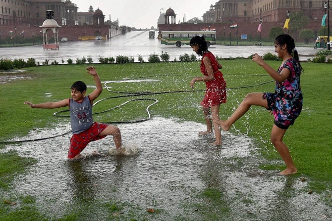 दिल्लीतील विजय चौक येथे मुसळधार पावसात खेळण्याचा आनंद लुटताना लहान मुले. (छायाः पीटीआय)