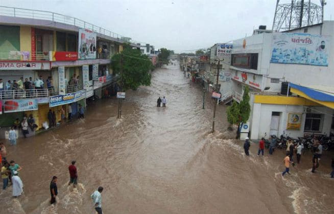 गुजरातमधील गोंडल येथील लोकांना पुराच्या पाण्यातून अशाप्रकारे वाट काढावी लागत होती. (छाया- पीटीआय)