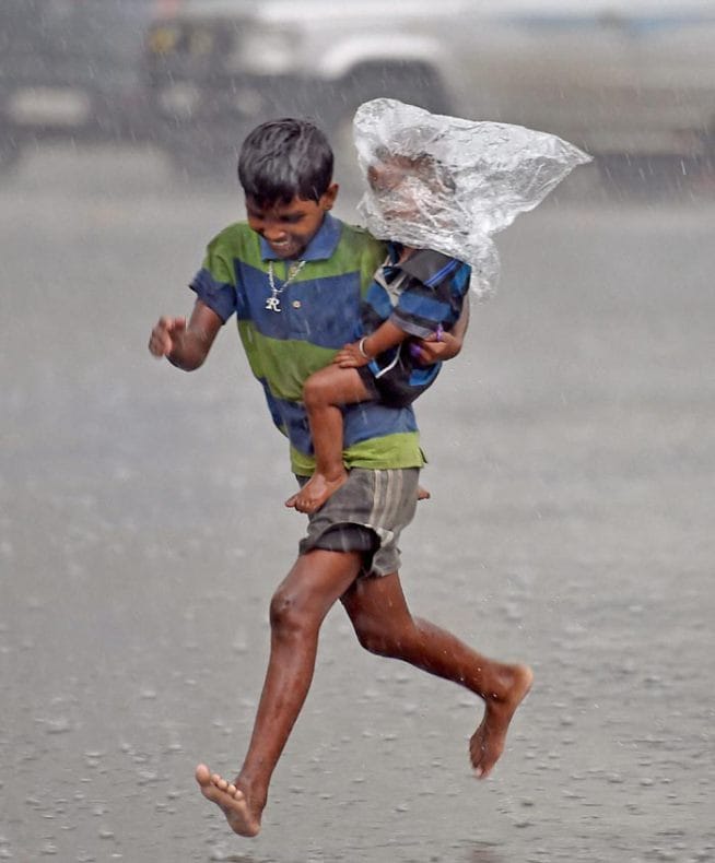 आपला लहान भाऊ पावसात भिजू नये म्हणून कोलकात्त्यामधील हा लहान मुलगा भावाच्या डोक्यावर प्लॅस्टिकची पिशवी घालून धावताना. (छाया- पीटीआय)