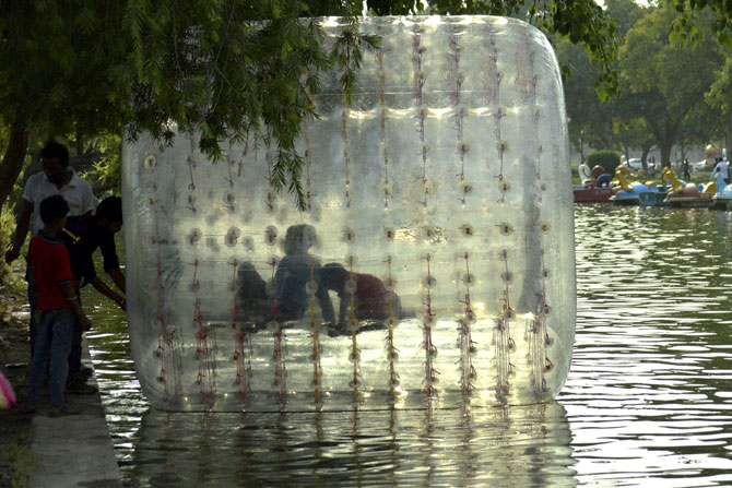 नवी दिल्ली येथील 'इंडिया गेट'जवळ 'बलून बोट राईड' चा आनंद लुटताना पर्यटक. (छाया-पीटीआय)