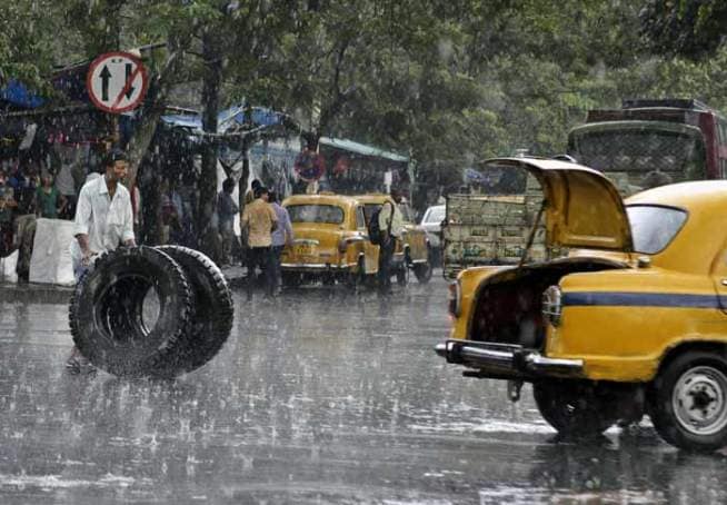 डोक्यावर मुसळधार पाऊस पडत असताना ट्रकचे टायर्स टॅक्सीमध्ये ठेवण्यासाठी निघालेला हा माणूस. (छाया- एपी)