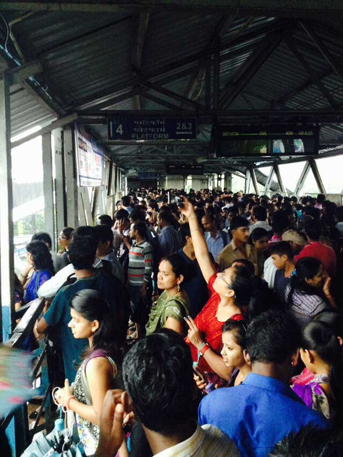 पावसापासून बचावासाठी रेल्वेच्या पूलावर उभ्या असलेल्या महिला. (छायाः अमित चक्रवर्ती)