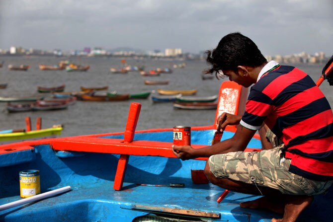नारळी पोर्णिमेची तयारी - पावसाळ्याच्या दीर्घ रजेनंतर नारळी पोर्णमेच्या दिवशी समुद्राला नारळ अर्पण करत कोळी बांधव पून्हा मासेमारीला सुरुवात करतात. नारळी पोर्णिमेसाठी होडी रंगवताना कोळी बांधव. (छाया- प्रशांत नाडकर)