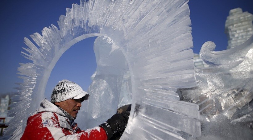 बर्फाच्या कलाकृतीला आकार देताना शिल्पकलाकार.
