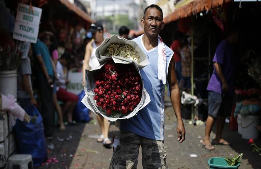 फिलिपाईन्स : एक दुकानदार हातात लाल रंगाचे गुलाब घेऊन जाताना या छायाचित्रात दिसत आहे.