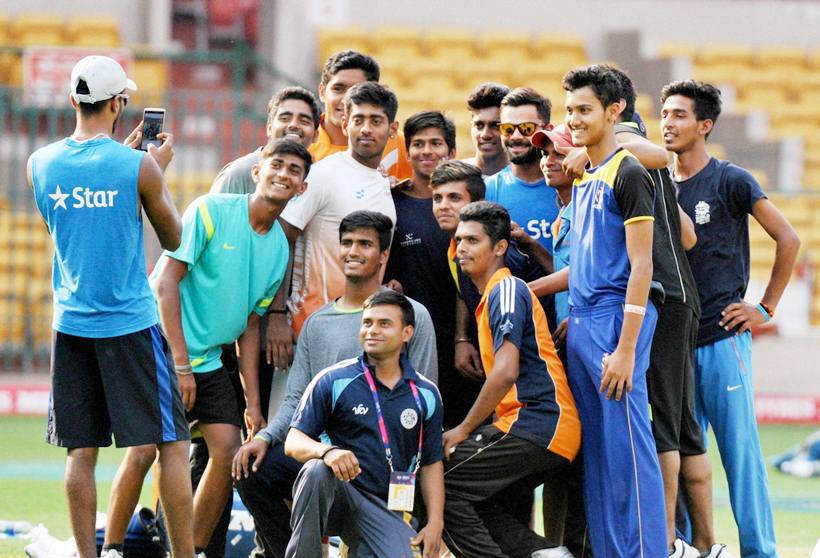 Bengaluru: Cricketer Virat Kohli poses with young cricketers as Hardik Pandya clicks their photo during a training session at Chinnaswamy Stadium in Bengaluru on Tuesday. PTI Photo by Shailendra Bhojak (PTI3_22_2016_000228B)