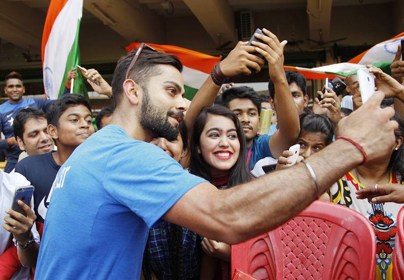 India's Virat Kohli takes a selfie with his fans after participating in a training session ahead of their ICC World Twenty20 2016 match against Bangladesh in Bangalore, India, Tuesday, March 22, 2016. (AP Photo/Aijaz Rahi)