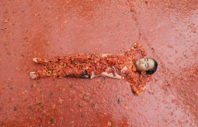 टोमॅटो फेस्टिव्हलदरम्यान टोमॅटोच्या पूलमध्ये निवांत झोपलेला मुलगा. (छाया सौजन्य : रॉयटर्स)