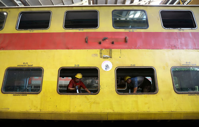 डबल डेकर ट्रेनला रंग देताना कर्मचारी