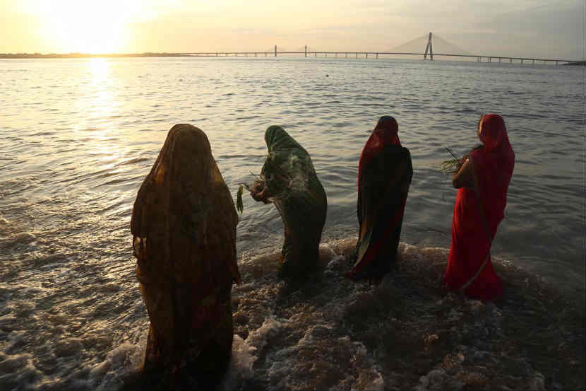 मावळत्या सुर्याच्या साक्षीने समुद्राच्या पाण्यात उभा राहून पूजा करणाऱ्या महिला