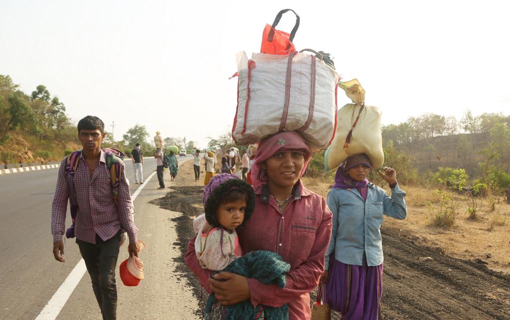डोक्यावर सामान आणि कडेवर मुलाला घेऊन घराची वाट पकडलेली महिला कामगार