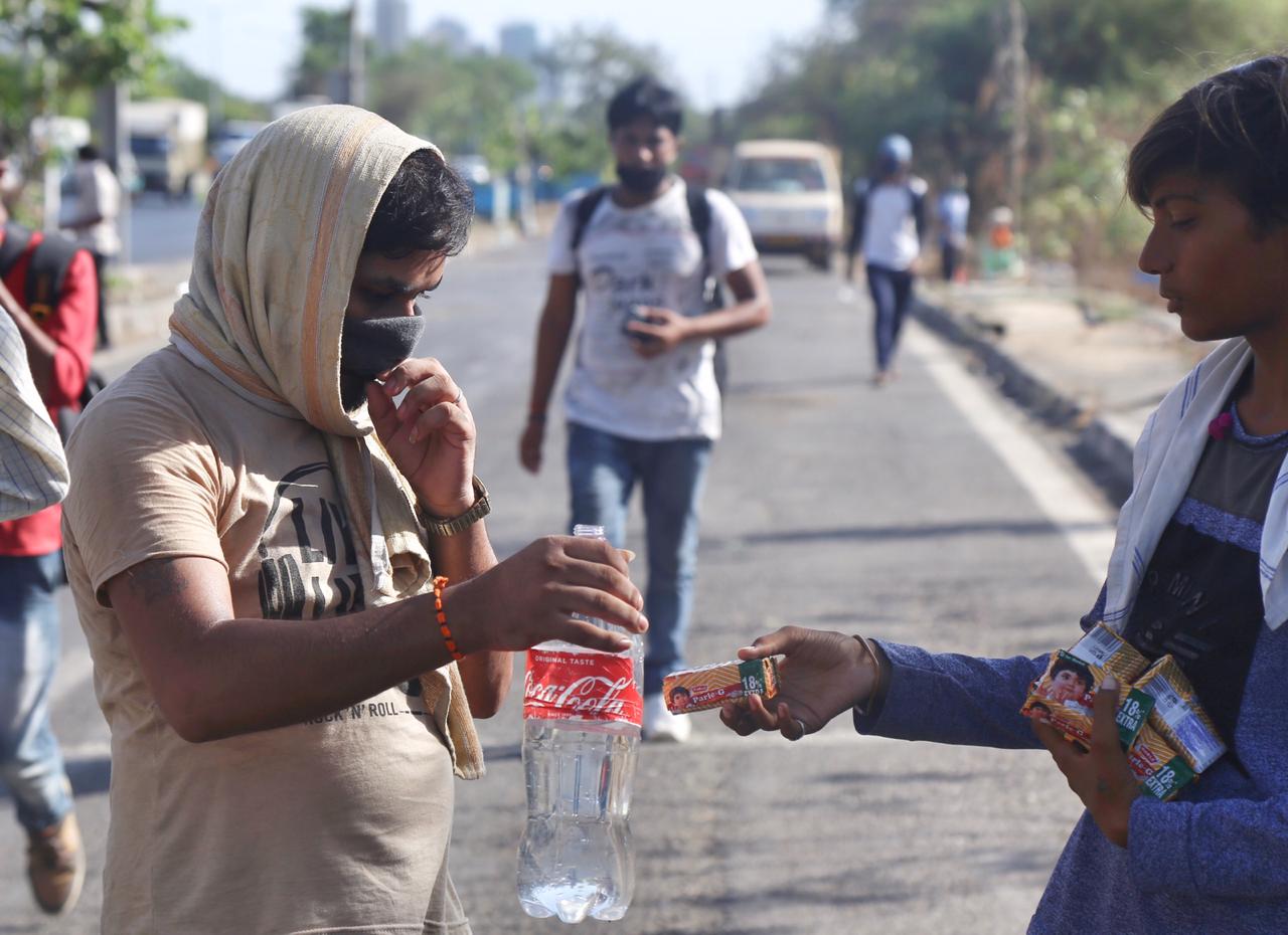 विक्रोळी भागात स्थानिक लोकं या कामगारांना बिस्कीटचे पुडे, पाण्याच्या बाटल्या देऊन मदत करत आहेत. (छायाचित्र - निर्मल हरिंद्रन)