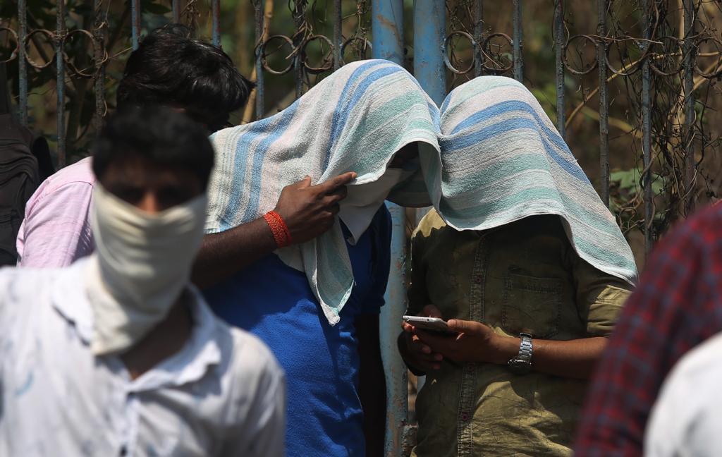रांगेत उभं असताना दिवसांत करोनाविषयक घडामोडींचा आढावा घेताना दोन कामगार