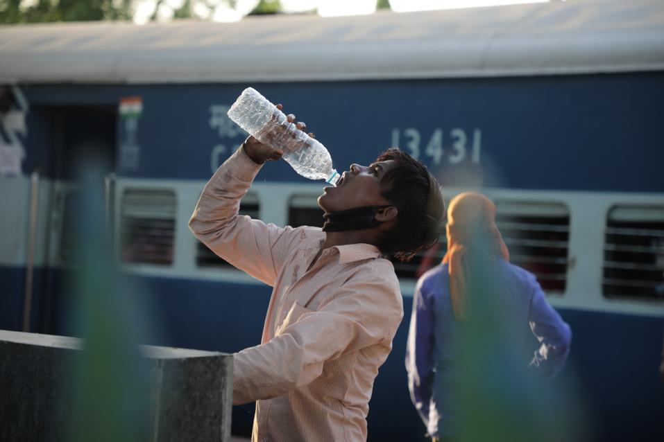 रेल्वे स्थानकावर पाणी पिणारा एक कामगार