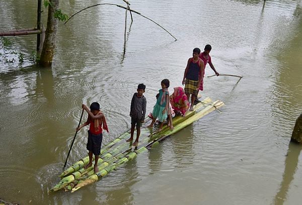 बांबू आणि झाडांच्या खोडाचा वापर करुन आपला बचाव करत बाहेर पडताना एक कुटुंब