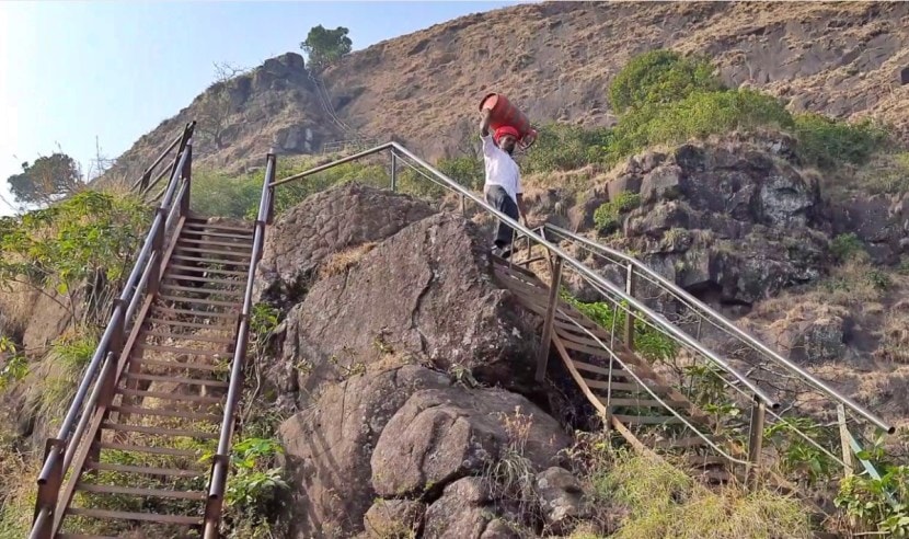 कारवाईनंतर चहासाठी कळसुबाई शिखरावर नेलेला गॅस सिलिंडर घेऊन पायथ्याशी जाताना आदिवासी.