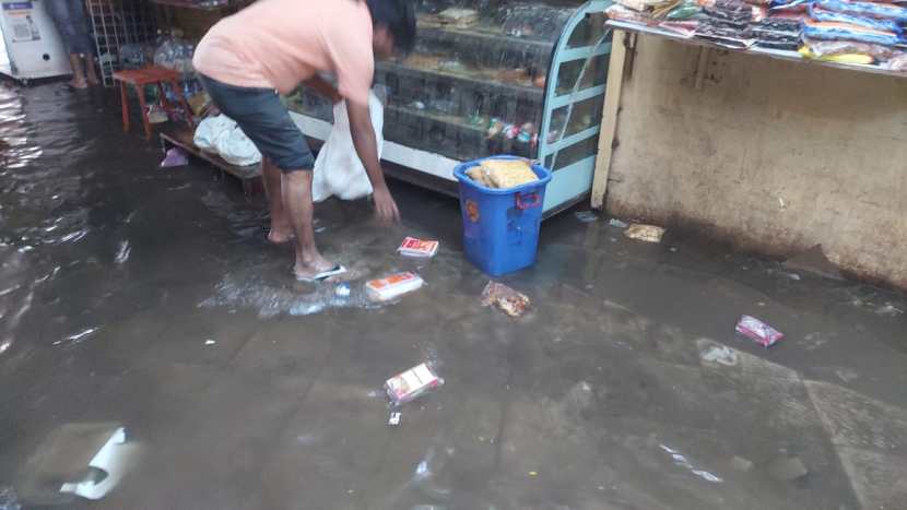 दुकानात शिरलेले पावसाचे पाणी काढताा दुकानदारांना मोठी कसरत करावी लागली.