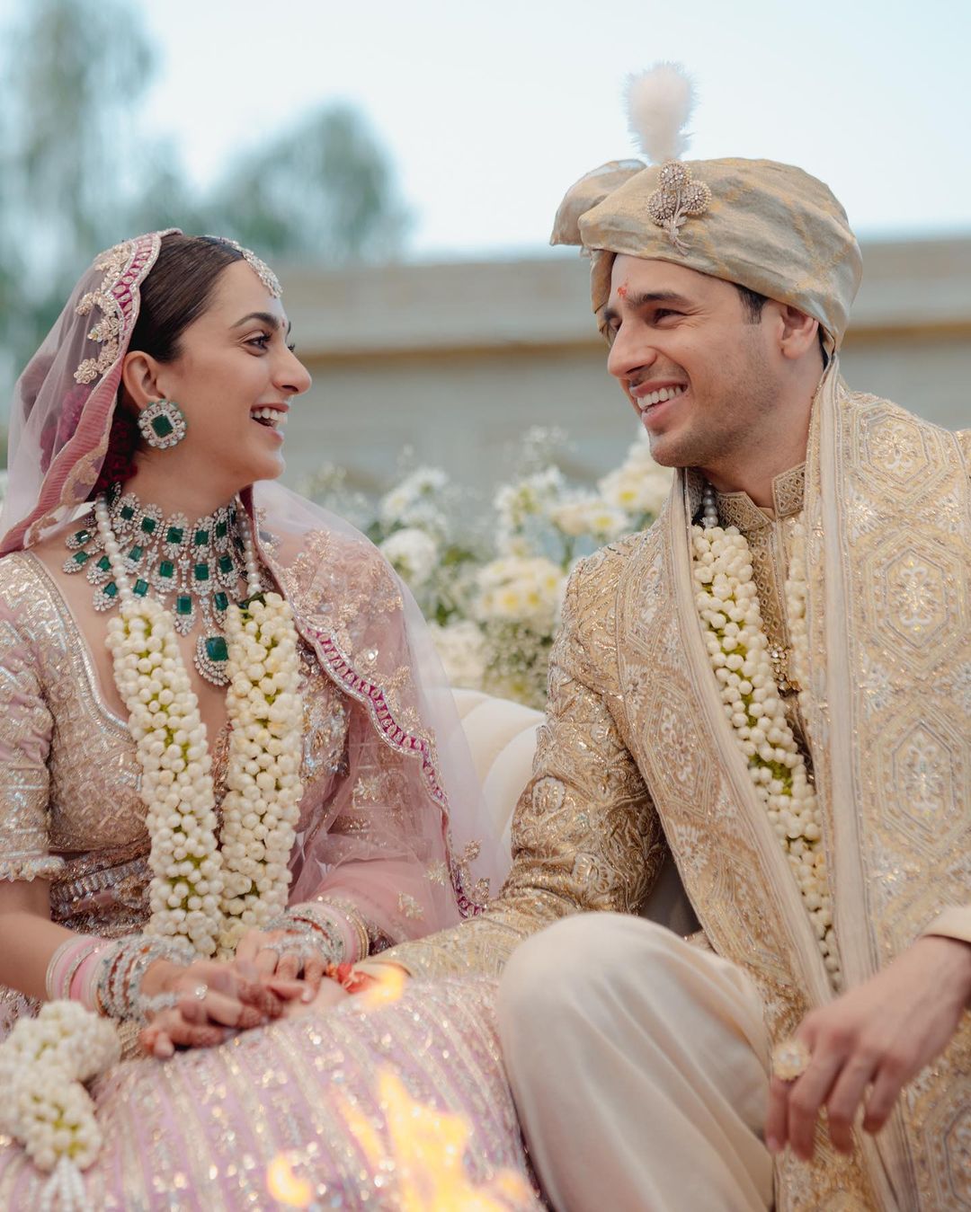 Photo of A bride in a pretty pink lehenga and groom in white sherwani.