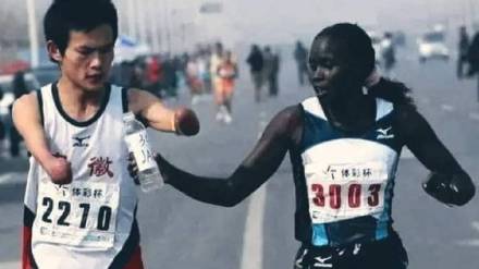 female athlete serving water to disabled runner