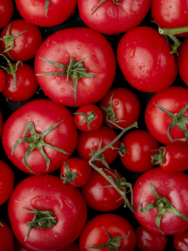 top view of ripe fresh tomatoes with water drops on black background