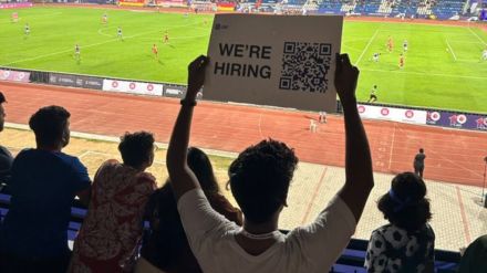 Man holds were hiring placard during football match in Bengaluru