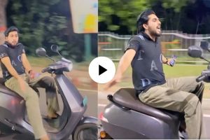 a young man dance on moving scooty by leaving handle