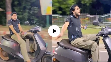 a young man dance on moving scooty by leaving handle