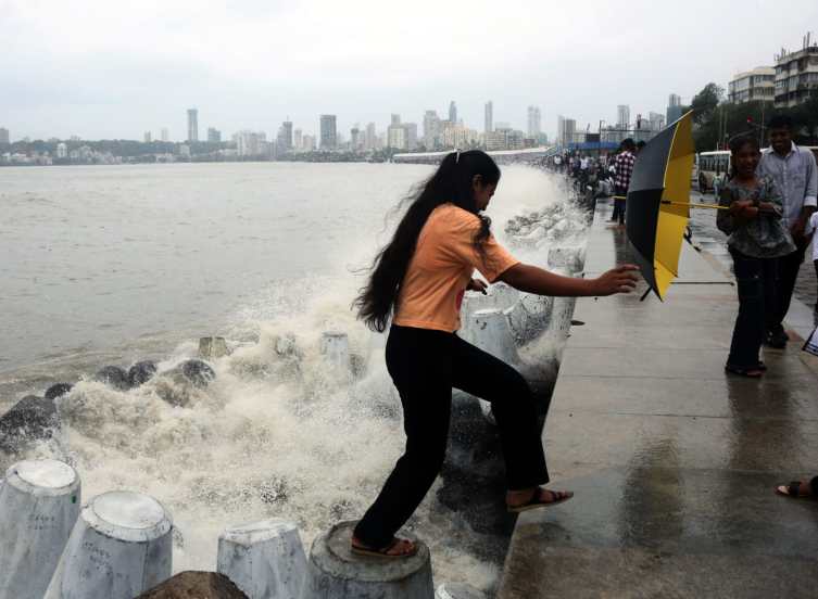 People holding umbrella enjoying amid rains, in Marin Drive, Mumbai