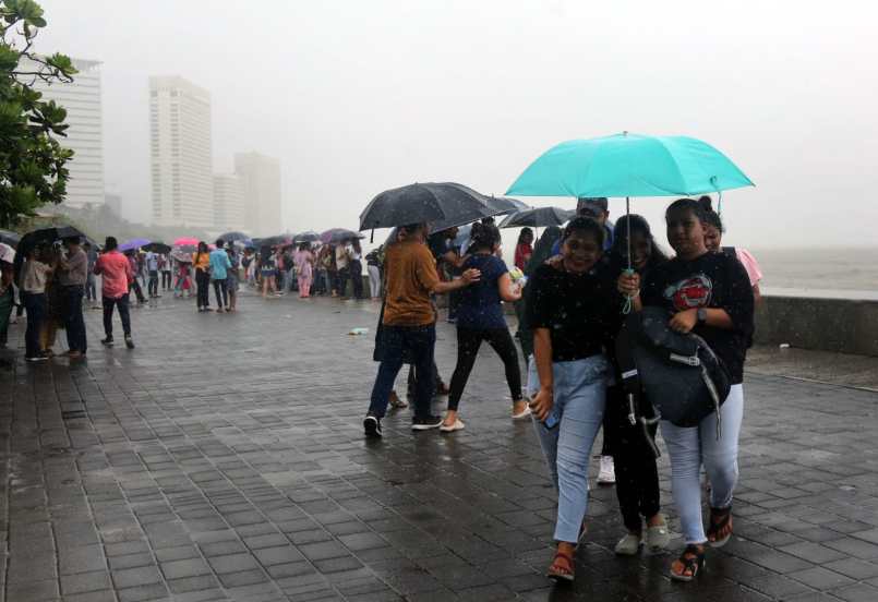 People holding umbrella enjoying amid rains, in Marin Drive, Mumbai