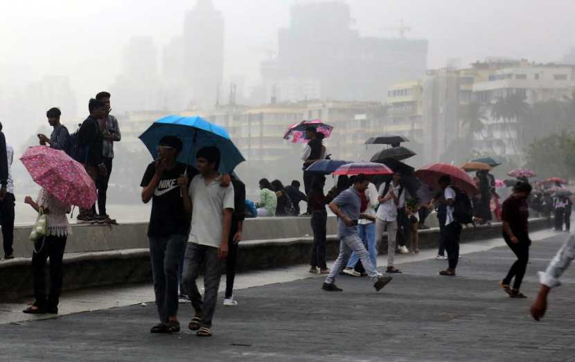 People holding umbrella enjoying amid rains, in Marin Drive, Mumbai