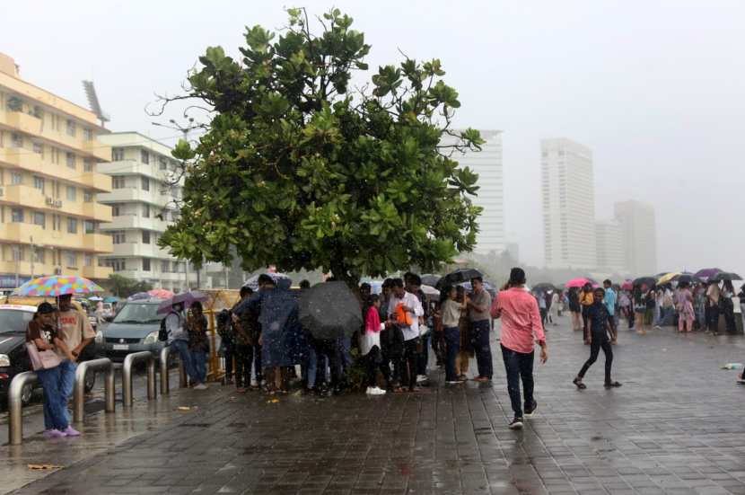 People holding umbrella enjoying amid rains, in Marin Drive, Mumbai