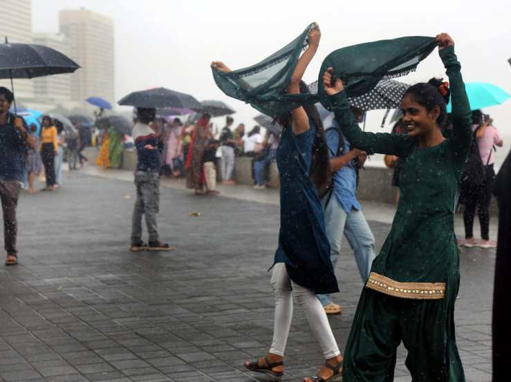 People holding umbrella enjoying amid rains, in Marin Drive, Mumbai