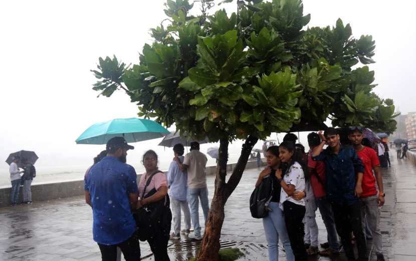 People holding umbrella enjoying amid rains, in Marin Drive, Mumbai