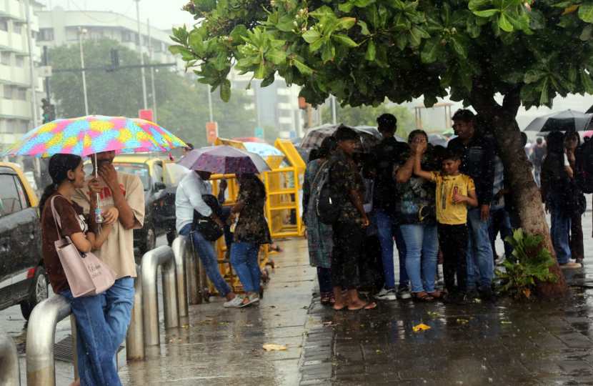 People holding umbrella enjoying amid rains, in Marin Drive, Mumbai