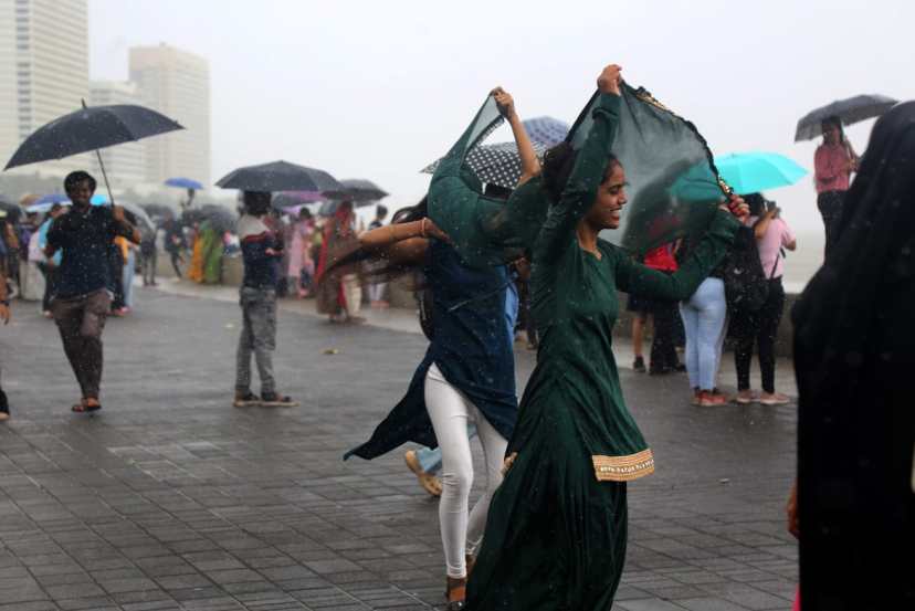 People holding umbrella enjoying amid rains, in Marin Drive, Mumbai