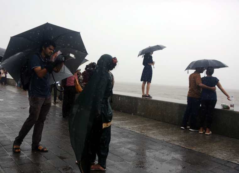 People holding umbrella enjoying amid rains, in Marin Drive, Mumbai