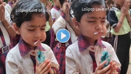 a little student eating Lollipop while standing for prayer at school