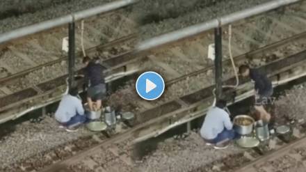 Video Shows Man standing near by railway track and preparing food with foot