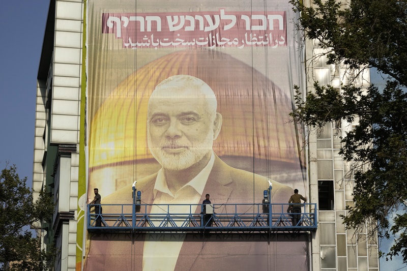 Iranian workers install a huge banner on a wall showing a portrait of Hamas leader Ismail Haniyeh and the Dome of Rock Mosque at the Al-Aqsa Mosque compound of Jerusalem with a sign which reads in Farsi and Hebrew: "Wait for severe punishment," at Felestin (Palestine) Sq. in Tehran, Iran, Wednesday, July 31, 2024.