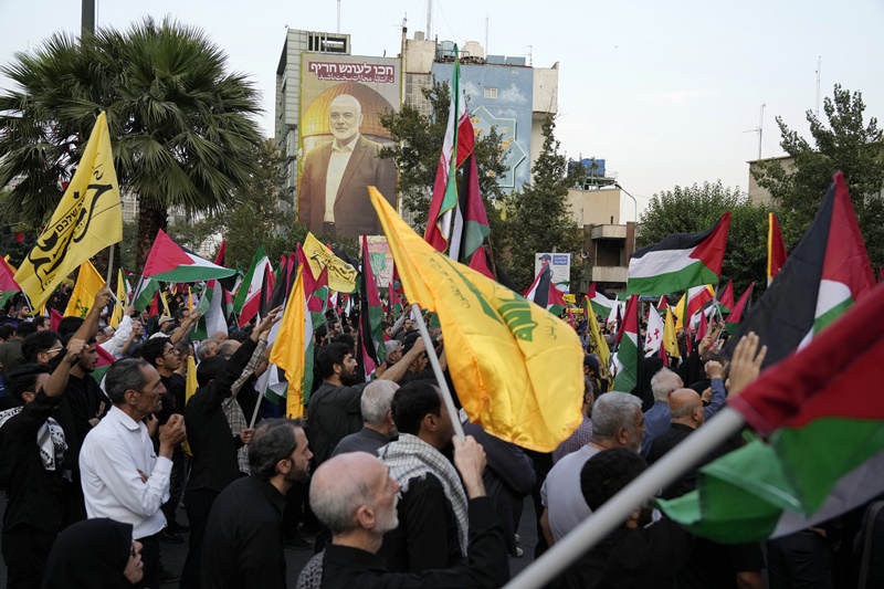 Iranian protesters wave Iranian, Palestinian and Lebanon's militant Hezbollah group flags in a demonstration to condemn the killing of Hamas leader Ismail Haniyeh as a huge portrait of him is seen on a wall at background, at Felestin (Palestine) Sq. in Tehran, Iran, Wednesday, July 31, 2024.