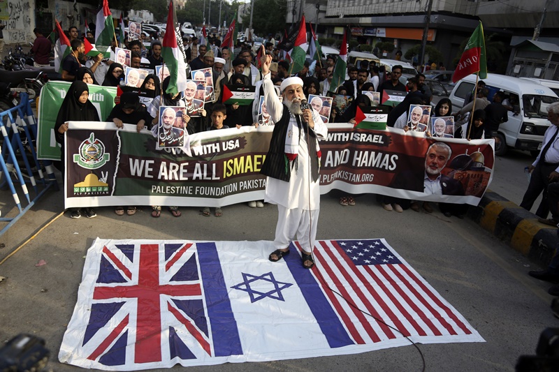 A supporters of the Pakistani Shiite Muslim group 'Imamia Student Organization' and 'Palestine Foundation Pakistan' stands on British, U.S. and Israeli flags in Karachi, Pakistan, Wednesday, July 31, 2024 during a protest to condemn the death of Hamas leader Ismail Haniyeh.