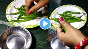 Kitchen jugad video woman is cutting green chillies by holding a wooden spoon in her thumb