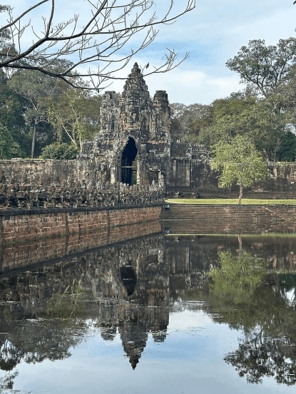 South gate of Angkor Thom along with a bridge of statues of gods and demons. Two rows of figures each carry the body of seven-headed naga.